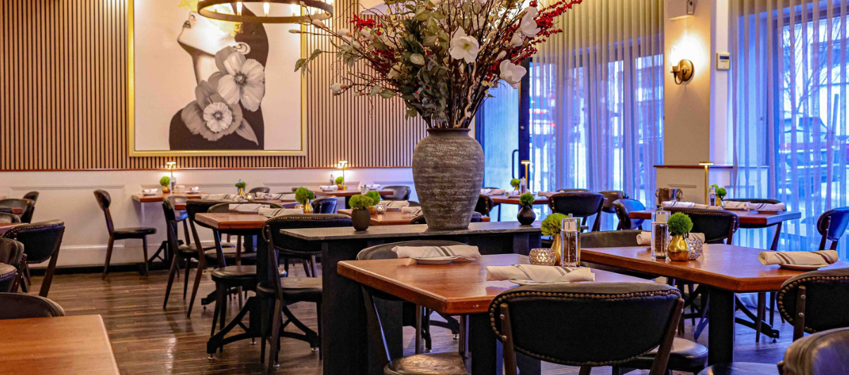 Modern restaurant dining room with floral centerpiece and wall art.