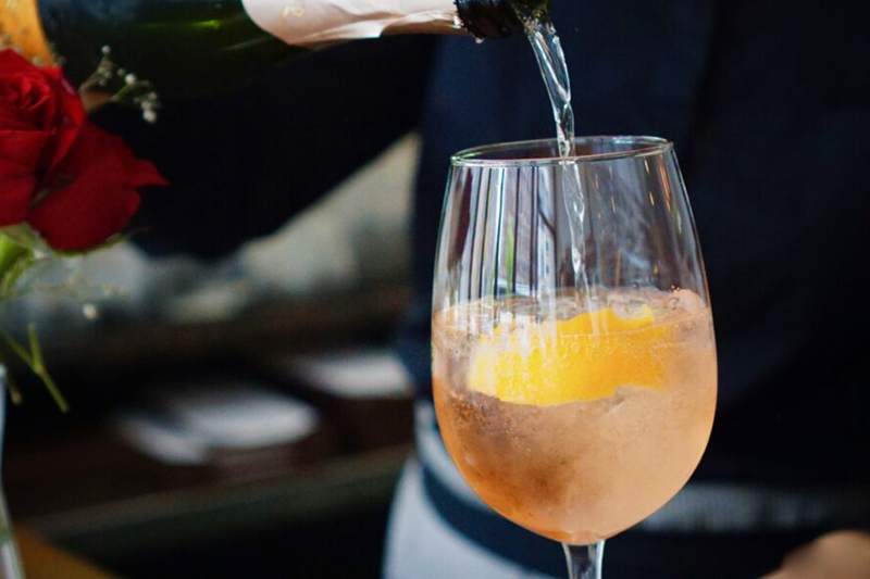 Prosecco being poured into a spritz with orange slice
