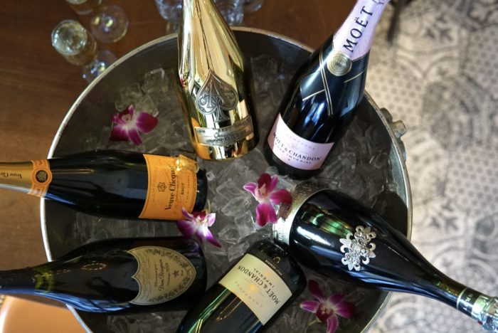 Bucket of ice holding luxury champagne bottles with orchids, including Dom Perignon and Veuve Clicquot.
