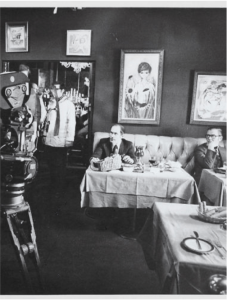 Black and white behind-the-scenes image of a restaurant scene being filmed for The French Connection (1971 Best Picture), inside the restaurant called Copain