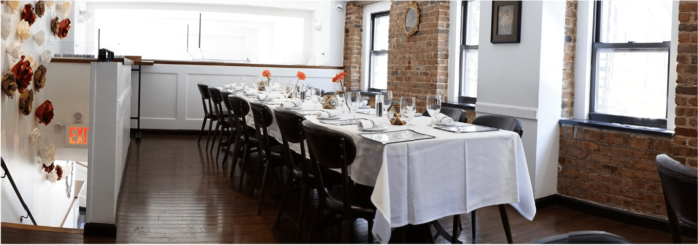 Sunlit mezzanine table set for private lunch at one long table with tablecloth