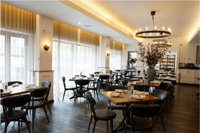 Main dining room with sheer drapes, candelabrum chandeliers, and spacius wooden tables