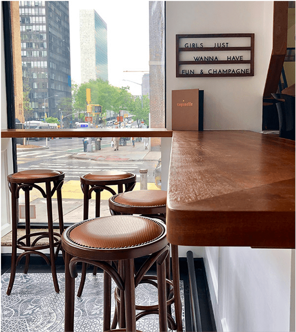 Counter-height bar stools by a window with a city street view