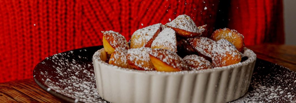 Bowl of madelines dusted with powdered sugar on a plate
