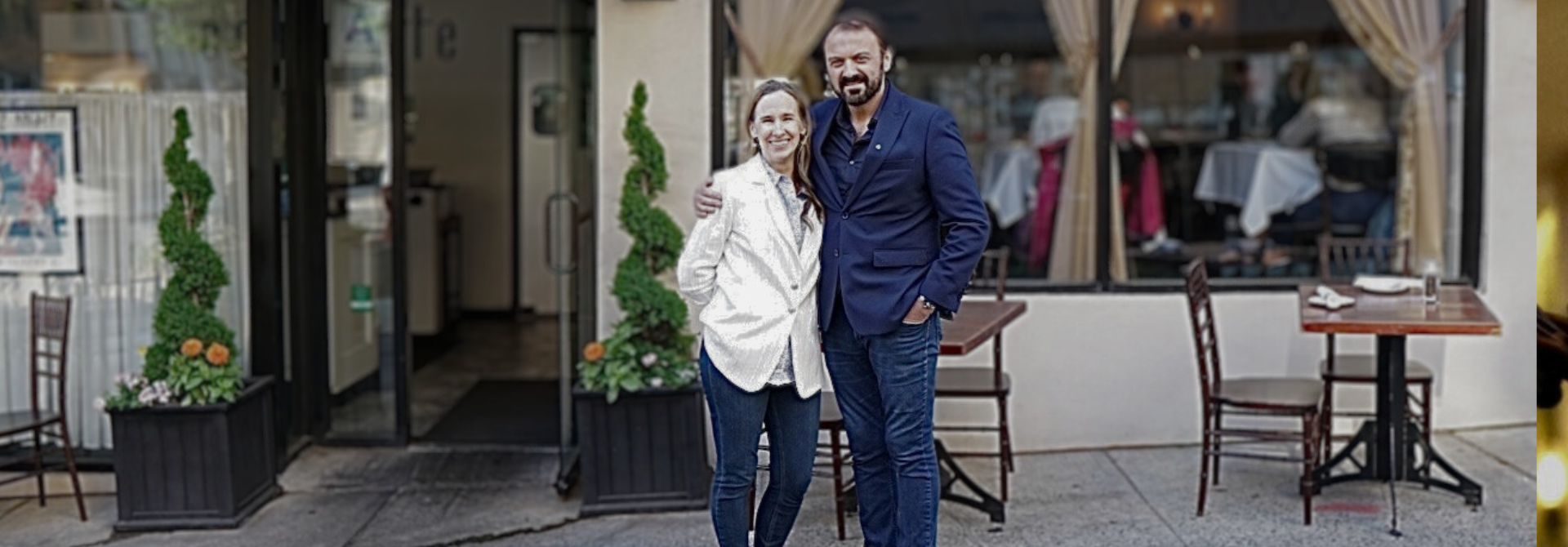 Co-owners Amy and Andrew standing together outside their restaurant, smiling in front entrance on the restaurants 7th anniversary