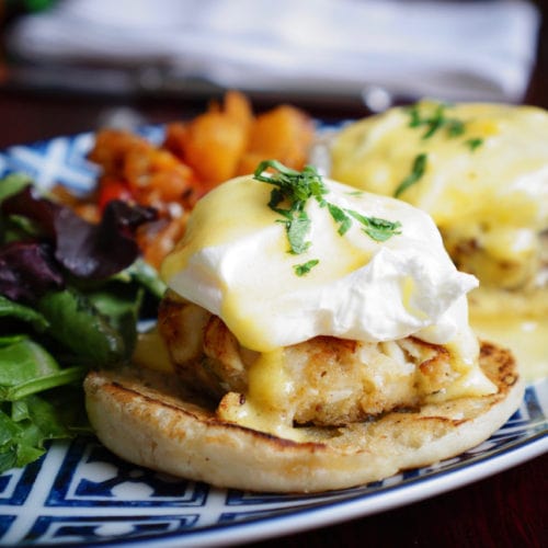 Crab cake eggs Benedict with hollandaise and mixed greens
