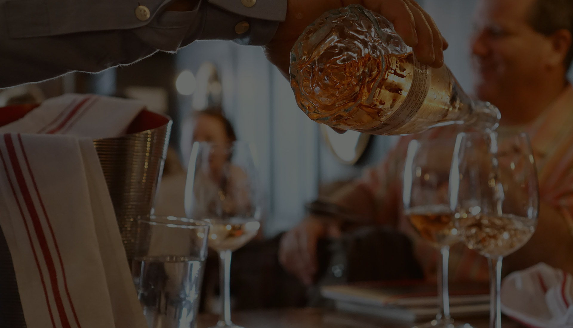 Rosé wine being poured into glasses at a restaurant table.