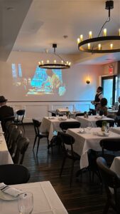 Dining room filled with diners while watching a movie on a pull down projector