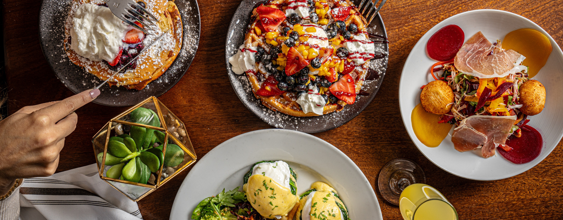 Overhead table view with brunch dishes, waffles and eggs Benedict