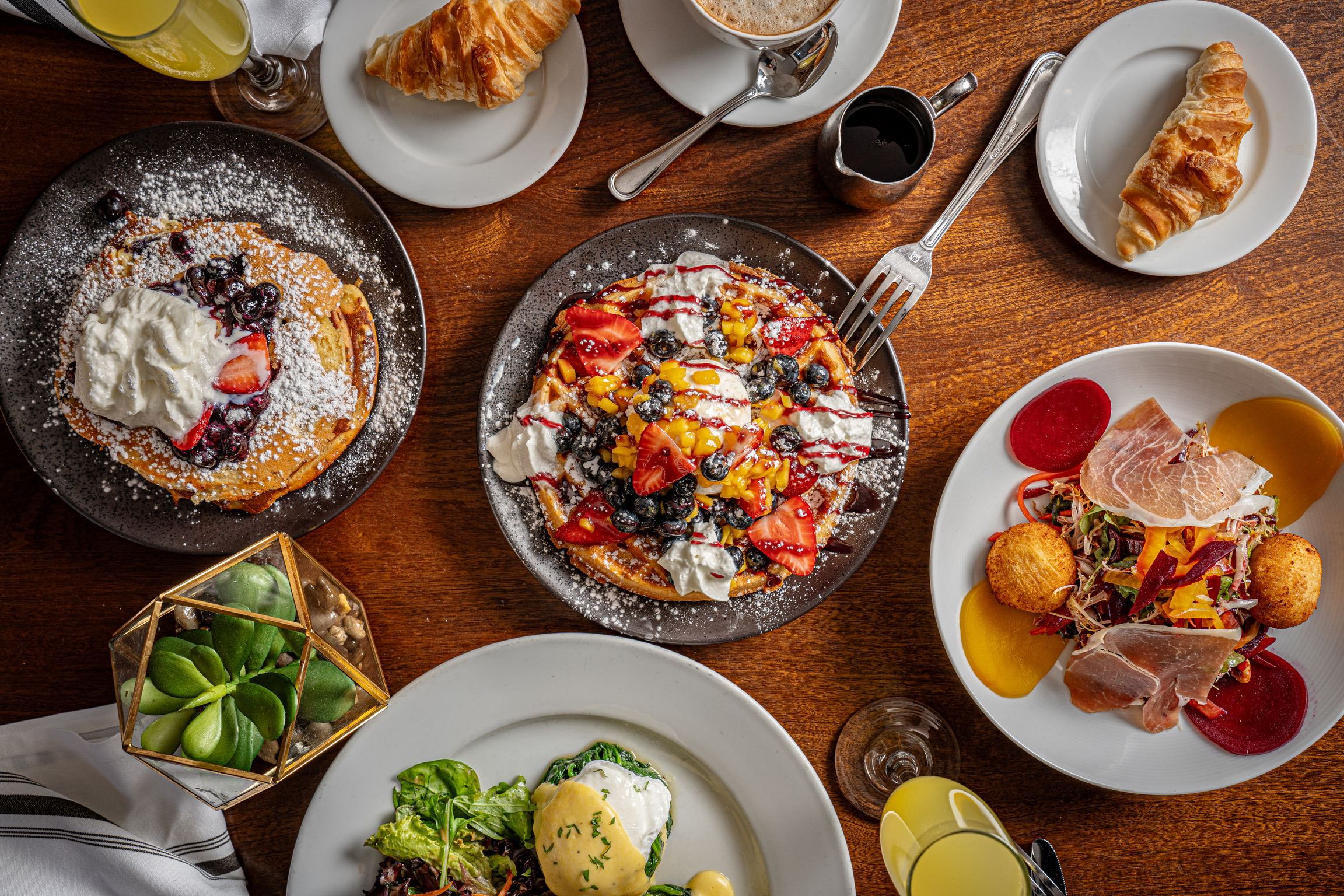 Overhead table view with brunch dishes, waffles and eggs Benedict