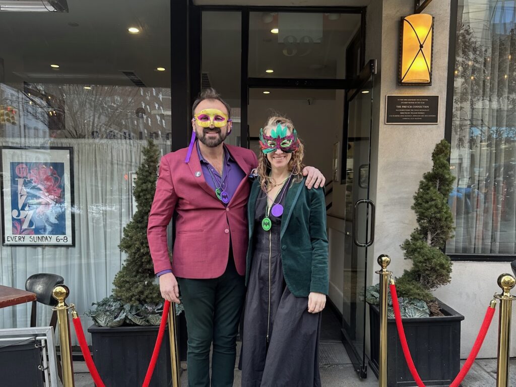 guests standing in front of restaurant with Mardi Gras masks