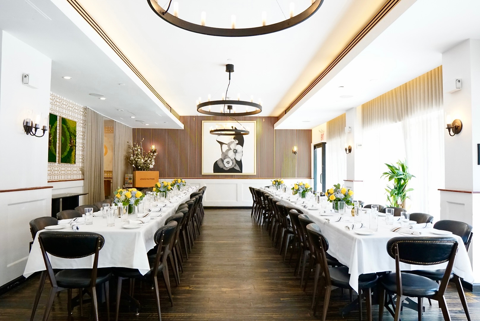 Elegant private dining room with two long banquet tables set with white linens and floral centerpieces